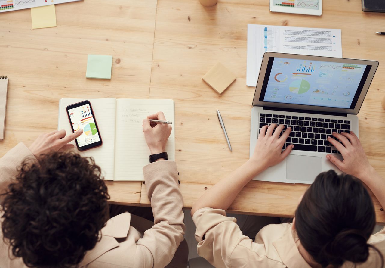 creative Overhead shot of two colleagues collaborating with devices and notes in a business meeting.