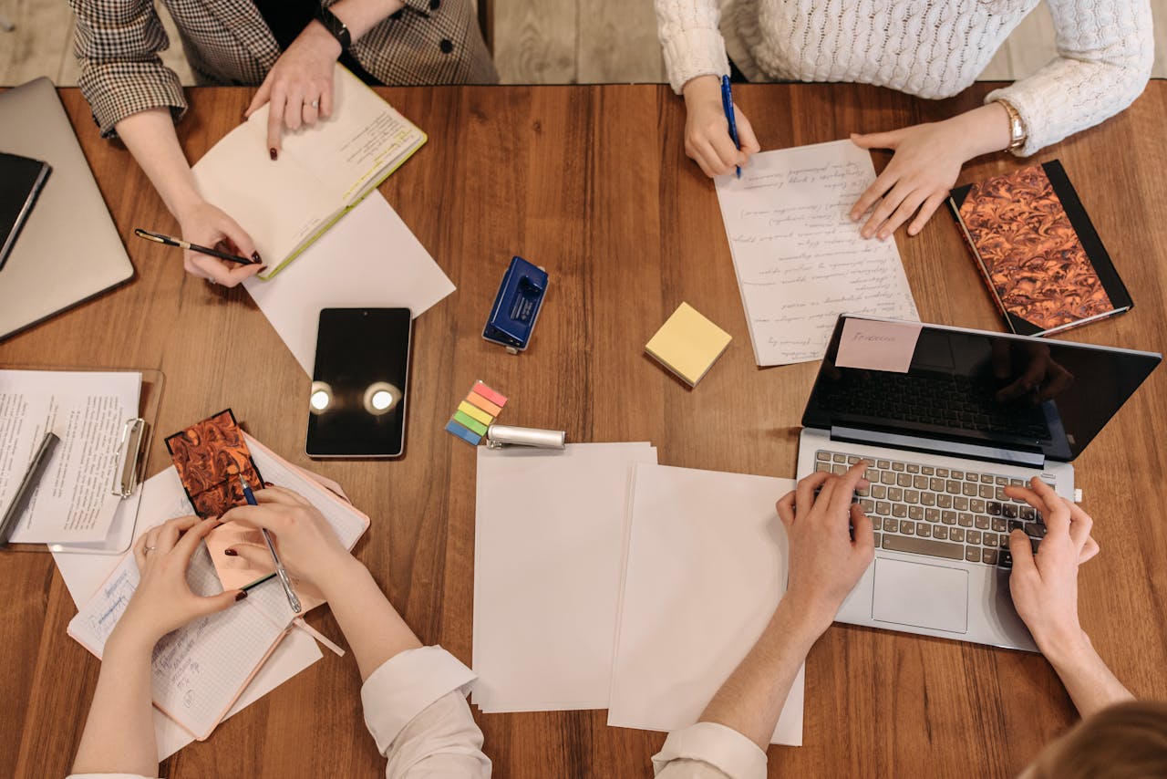 Top view of a team planning and working together in an office setting with laptops and notepads.