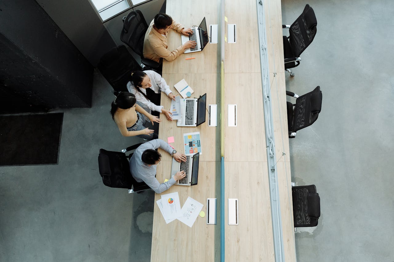 Services-03 High angle view of colleagues working together on laptops in a modern office setting.
